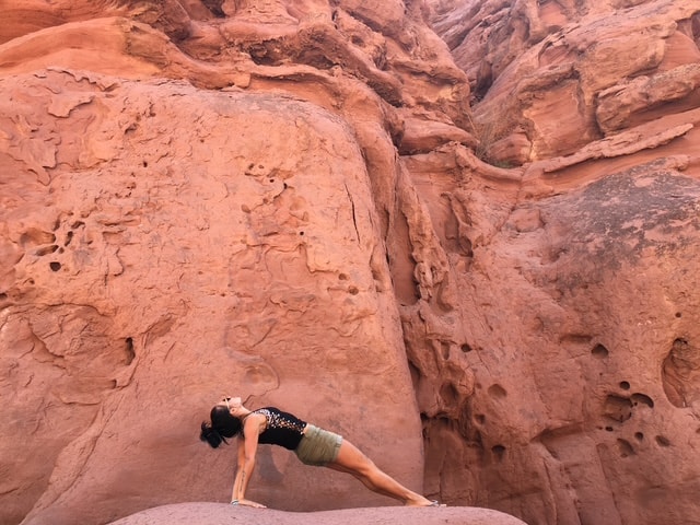 Julia in a plank pose against the red sandstone walls of Talampaya